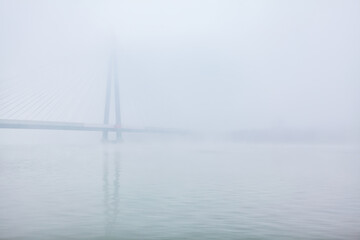 Bridge over the river in a foggy winter morning