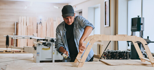 Carpenter works with wood in carpentry workshop. Man doing woodwork professionally - obrazy, fototapety, plakaty