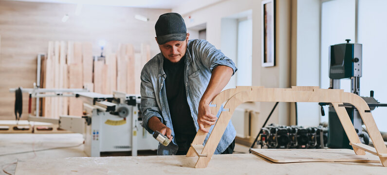 Carpenter works with wood in carpentry workshop. Man doing woodwork professionally