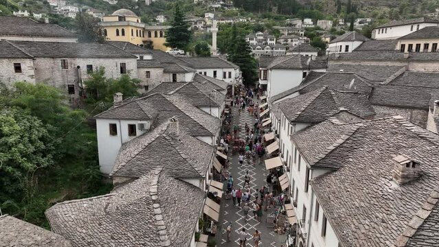 Aerial Drone Shot of the central streets in Gjirokastra, Albania. Crowded Center, Souvenir shop, Cafe, Tourist walking
