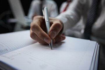 Businessman writes with a pen in diary, business and education concept. Close up