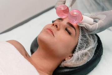 Anonymous crop beautician using ice globes acne removal on face of female client in spa