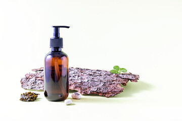 bottle with pump, tree bark and moss on a light background