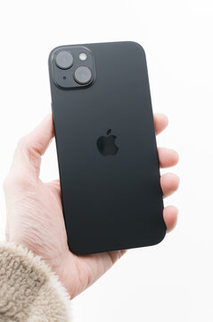 immagine editoriale illustrativa primo piano di mano che regge Apple iphone 15 plus su superficie sfondo bianca