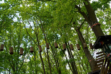 Children's Adventure Park bridges, ropes and stairs designed for beginners in woods among tall trees. Adventure climbing on high wired park. Course of high ropes in forest.