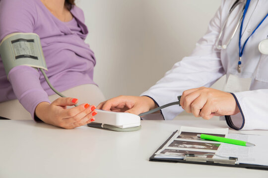 A pregnant girl at a doctor's appointment measures blood pressure. The concept of arterial hypertension and hypotension during pregnancy, preeclampsia. Copy space for text