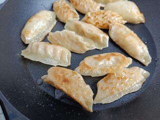 plusieurs gyoza cuisant dans une poêle