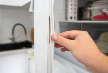 Replacing the torn sealing rubber on the refrigerator door with a new rubber. - obrazy, fototapety, plakaty