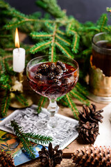 Jam from young pine cones in syrup on a background with pine branches