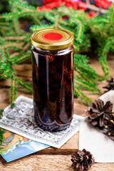Jam from young pine cones in syrup on a background with pine branches