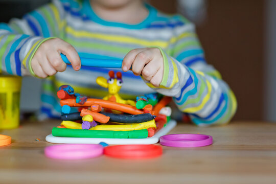 Close-up of hands of little boy having fun with dough, colorful modeling clay. Creative leisure with children. during corona virus quarantine staying at home. Shelter in place, lockdown concept.