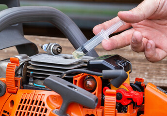 Injection of fuel from a syringe into the combustion chamber of a chainsaw. Checking the carburetor...