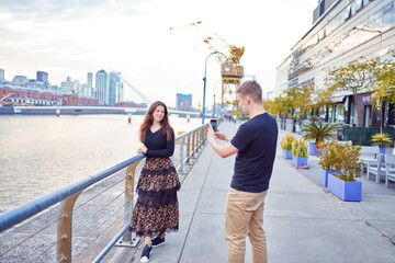 young caucasian man taking photos of his wife in Puerto Madero	