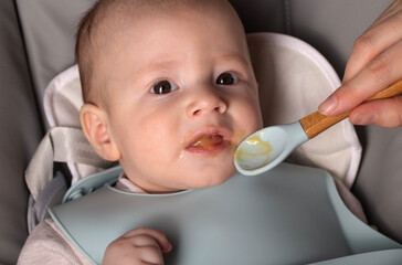 A small child of 5 months tries vegetable puree for the first time in his life, close-up