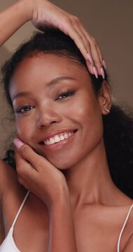 Vertical clip. Portrait of a black girl with curly hair, soft makeup and perfect skin. Beautiful face of young black woman with natural skin.