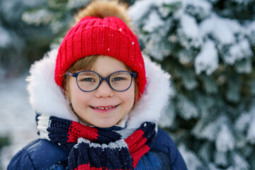 Small girl playing with snow. Happy preschool child in winter forest on snowy cold december day. Winter portrait of little preschooler in forest.