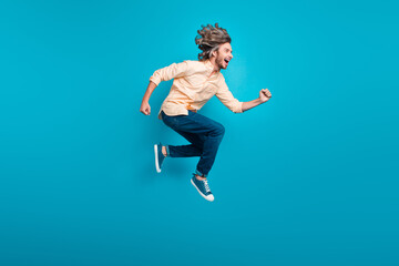 Fototapeta na wymiar Full length photo of active energetic guy wear stylish shirt flying run shopping look empty space isolated on blue color background