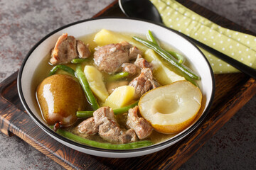 Swedish Lamb stew with fresh pears, potatoes, green beans close-up in a bowl on a wooden board. horizontal