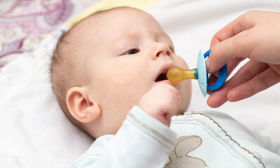 Little caucasian boy baby and dummy. Orthodontic pacifier for children. Formation of bite in children, close-up