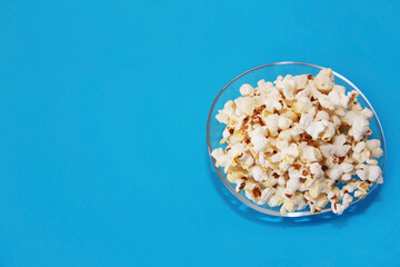 Delicious white airy fried popcorn in a plate on a blue background