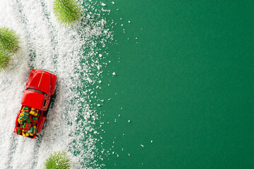 Winter Wonder: An overhead view of a small vintage red car laden with gifts weaving through a pine...