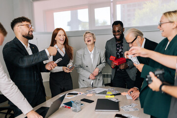 Happy multiethnic business team of mixed-aged coworkers having fun, jumping, rejoicing from successful ending start-up project, scattering money. Diverse staff having party celebrating victory