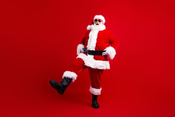 Fototapeta na wymiar Full length photo of energetic active santa claus in sunglass hold hands on waist dancing for children isolated on red color background