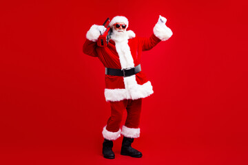 Full size photo of energetic grandfather wear santa costume in glasses hold boombox on shoulder have fun isolated on red color background