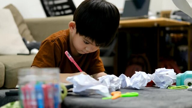 Asian boy drawing on table And there was a piece of paper left on the table.