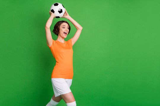 Profile portrait of astonished person arms hold ball above head open mouth look empty space isolated on green color background