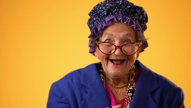 Closeup of funny happy smiling laughing crazy grandmother mature woman, 80s, acting isolated on yellow background