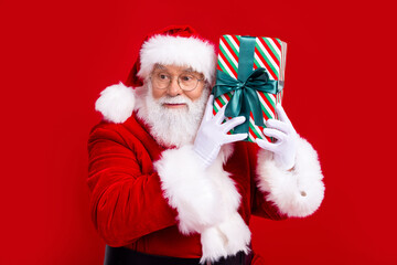 Photo of funky cool nice retired man saint nicholas hands hold giftbox interested listening isolated on red color background