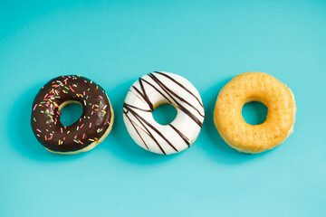 assorted donuts with chocolate frosting, topping sprinkles donuts Colorful variety and Variety of flavors mix of multi colored sweet donuts with frosted sprinkled on blue background. top view