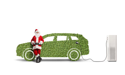 Santa claus leaning on a green car at a charging station