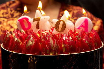 Bolo de aniversário de cor vermelha e preta com velas acesas.