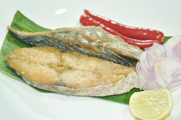 salty dry Indo-Pacific king mackerel fish topping chop shallot and chili with slice lemon salad on plate 