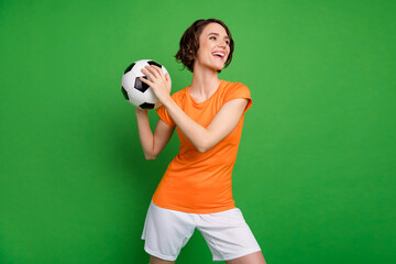 Fototapeta na wymiar Photo of charming satisfied girl arms hold ball look empty space toothy smile isolated on green color background