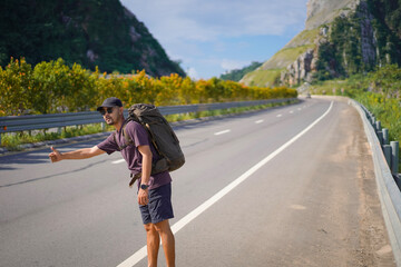 Fototapeta premium Tourist waving hand asking for help on the highway, Hitchhiking on the road, Travel man hitchhiking
