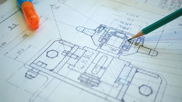 An engineer reads an old drawing of a moving part of industrial equipment. Close-up diagram. Macro.