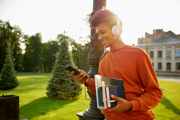 Side view portrait of happy smiling teenager student in headset using phone