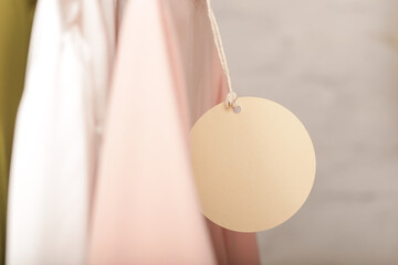 Close up of price tag of clothing item. Blank round label tag mockup on a clothes. Fashion industry...