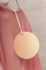 Close up of price tag of clothing item. Blank round label tag mockup on a clothes. Fashion industry...