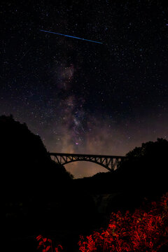 Train trestle at Letchworth State Park over the Genesee River at night with the Milky Way behind it.