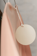 Close up of price tag of clothing item. Blank round label tag mockup on a clothes. Fashion industry...