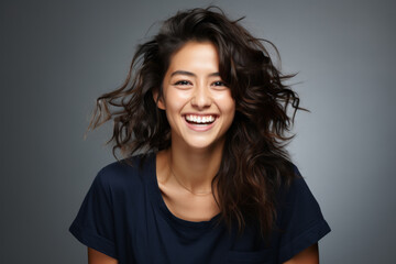 Retrato frontal de mujer joven  sonriente de rasgos asiáticos sobre fondo neutral. Copy space. - obrazy, fototapety, plakaty