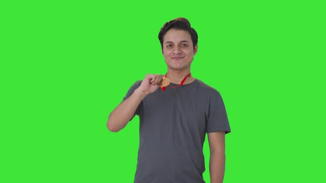 Happy Indian man posing with a medal Green screen