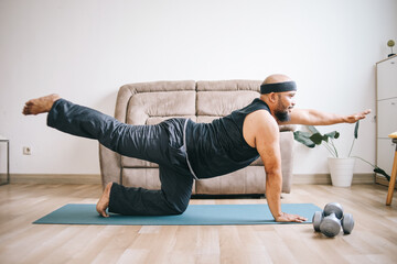 Funny fat bearded man in sportswear doing yoga or workout at home - obrazy, fototapety, plakaty