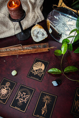 Oracle reading cards on red mat table with candles gemstones plants and encense