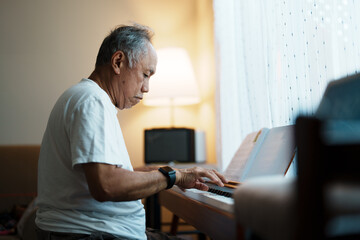 An older man is playing the piano in his free time. As a retiree, activities and hobbies are...
