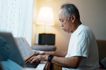 An older man is playing the piano in his free time. As a retiree, activities and hobbies are important.